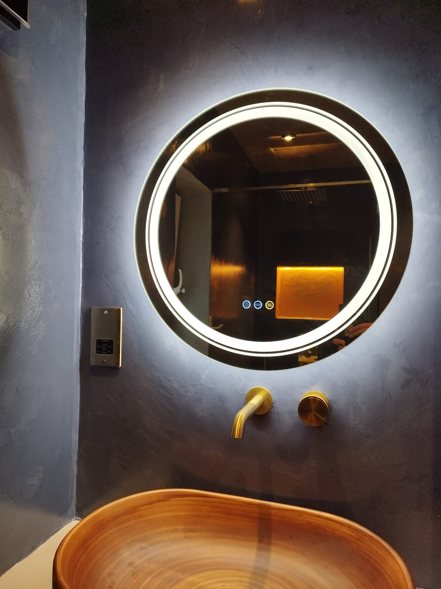 Dramatic microcement wall with illuminated mirror and basin